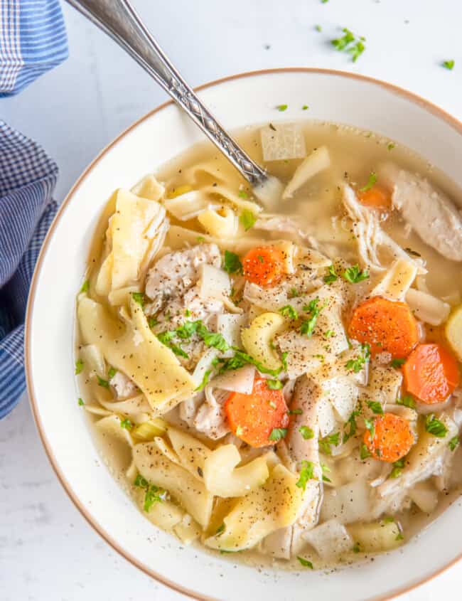 overhead view of crockpot chicken noodle soup in a white bowl with a spoon.