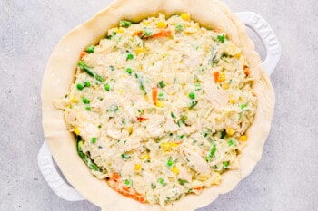 chicken pot pie on pie crust in a white pie pan.