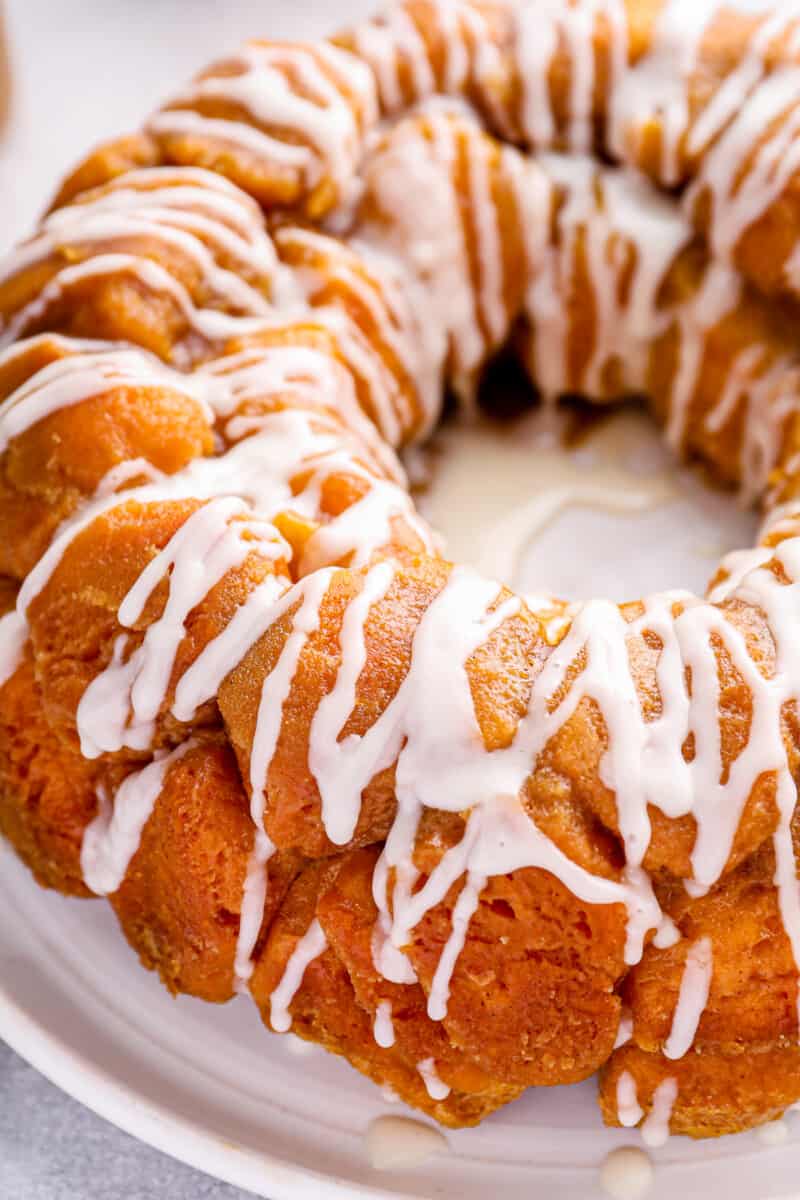 close up of iced easy monkey bread on a white serving plate.