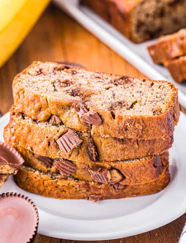 4 slices of reeses peanut butter cup banana bread stacked on a white plate.