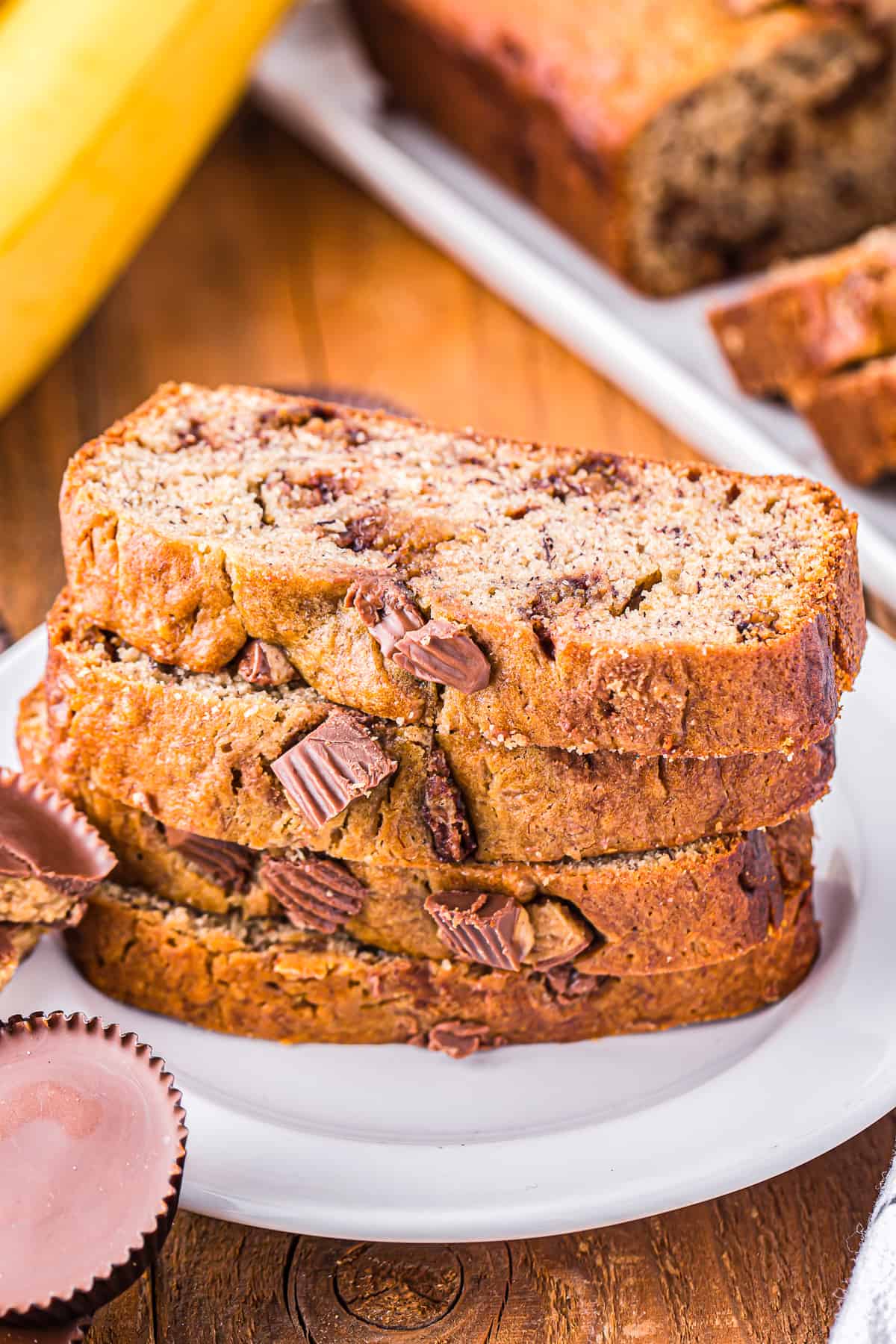 4 slices of reeses peanut butter cup banana bread stacked on a white plate.