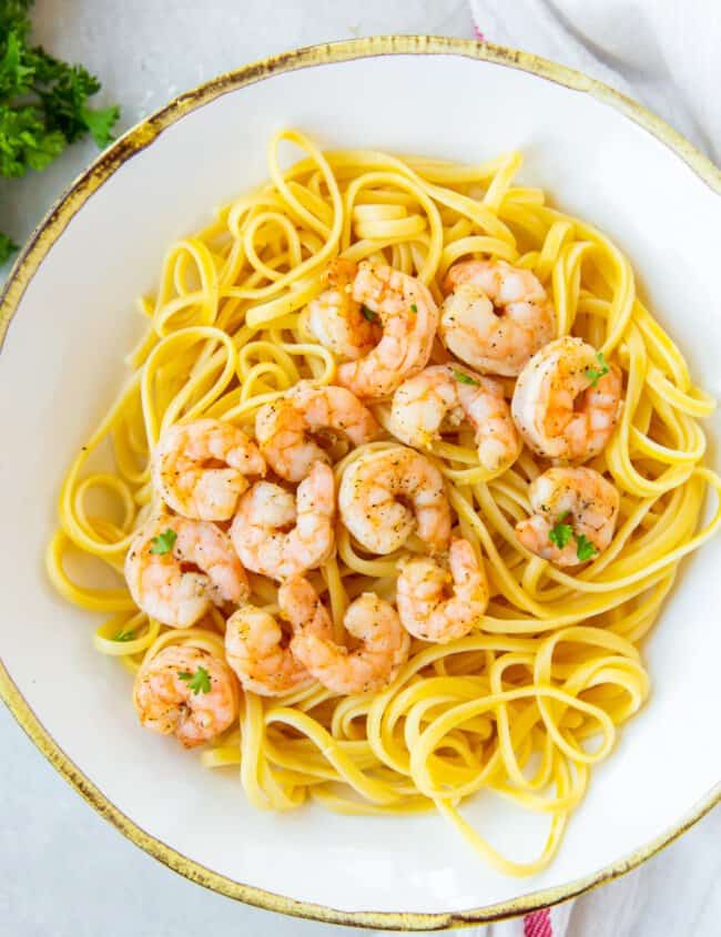 air fryer garlic shrimp over spaghetti on a white plate.