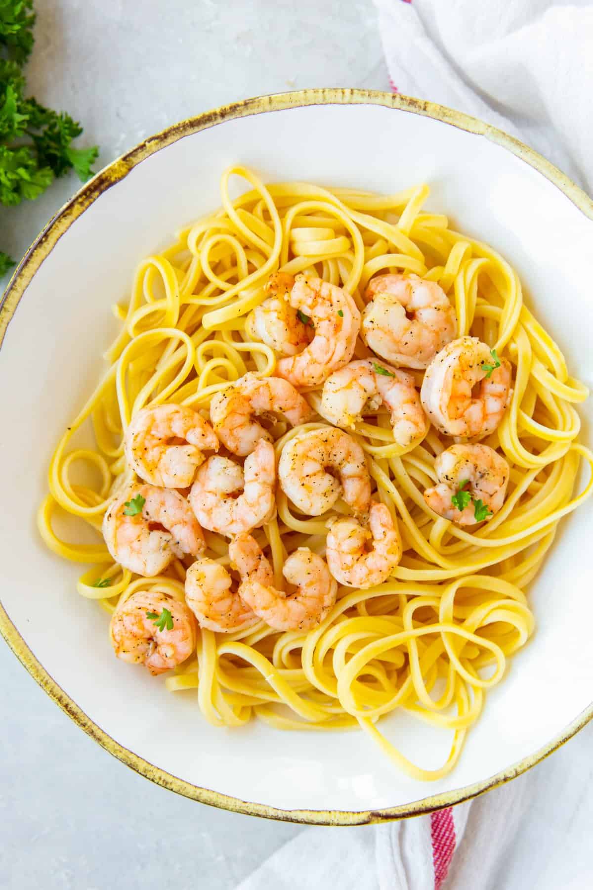 air fryer garlic shrimp over spaghetti on a white plate.