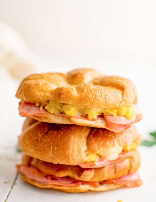 2 stacked croissant breakfast sandwiches on a table.