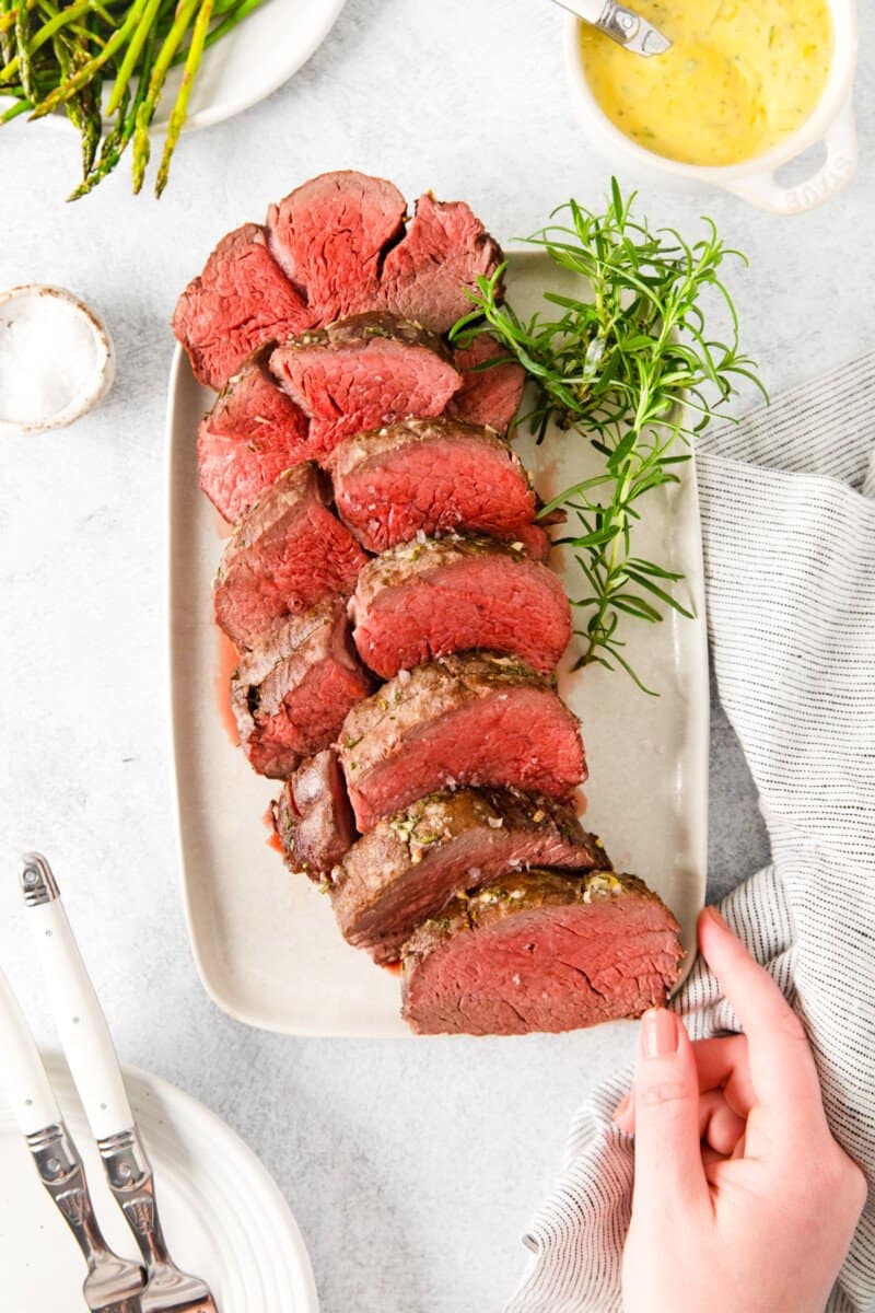 sliced crockpot beef tenderloin on a white plate.