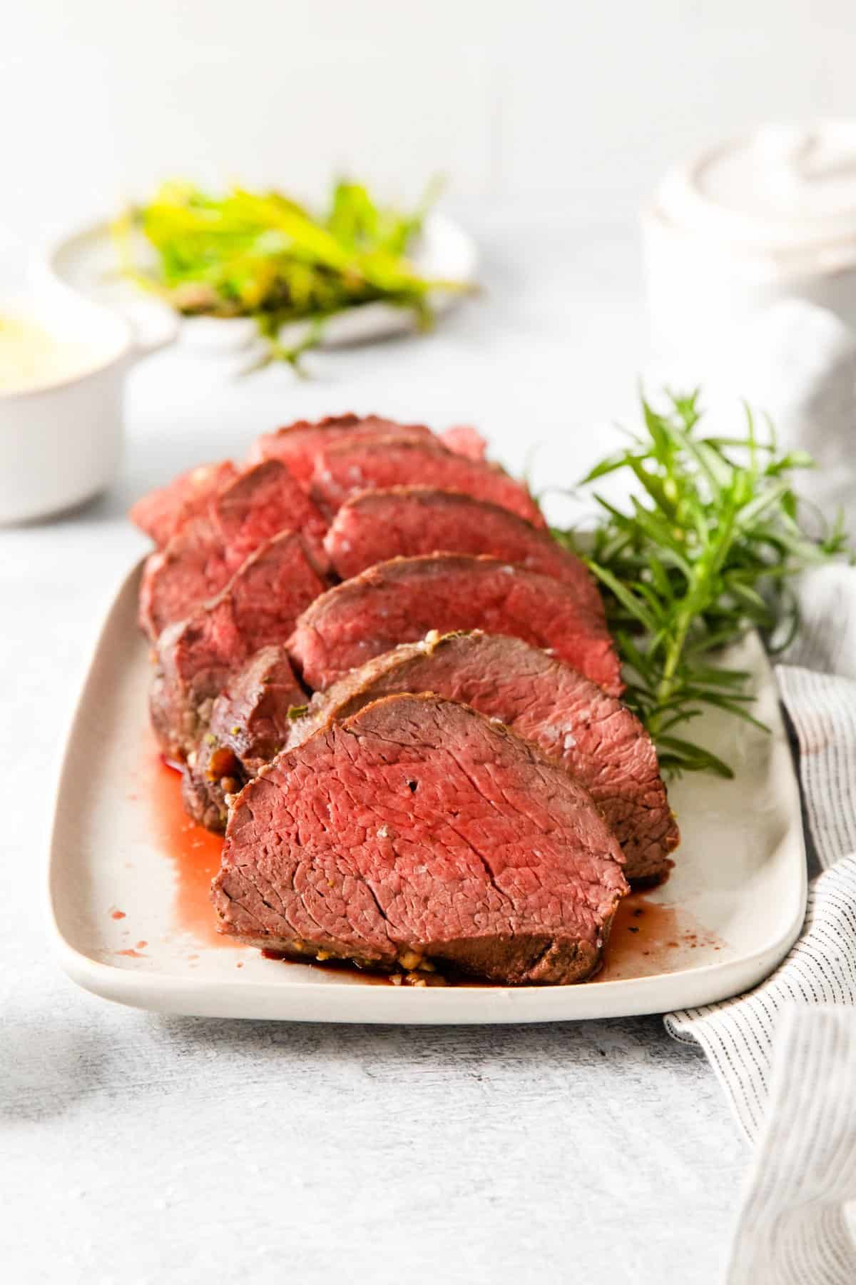 sliced crockpot beef tenderloin on a white plate.