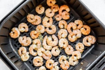 cooked shrimp in an air fryer basket.