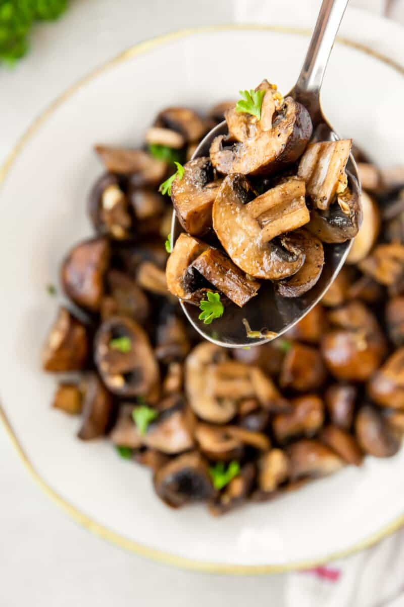 a spoonful of air fryer mushrooms in a white bowl.