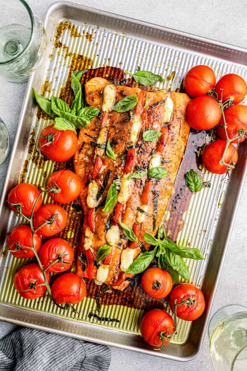 sheet pan with stuffed salmon and vines of tomatoes