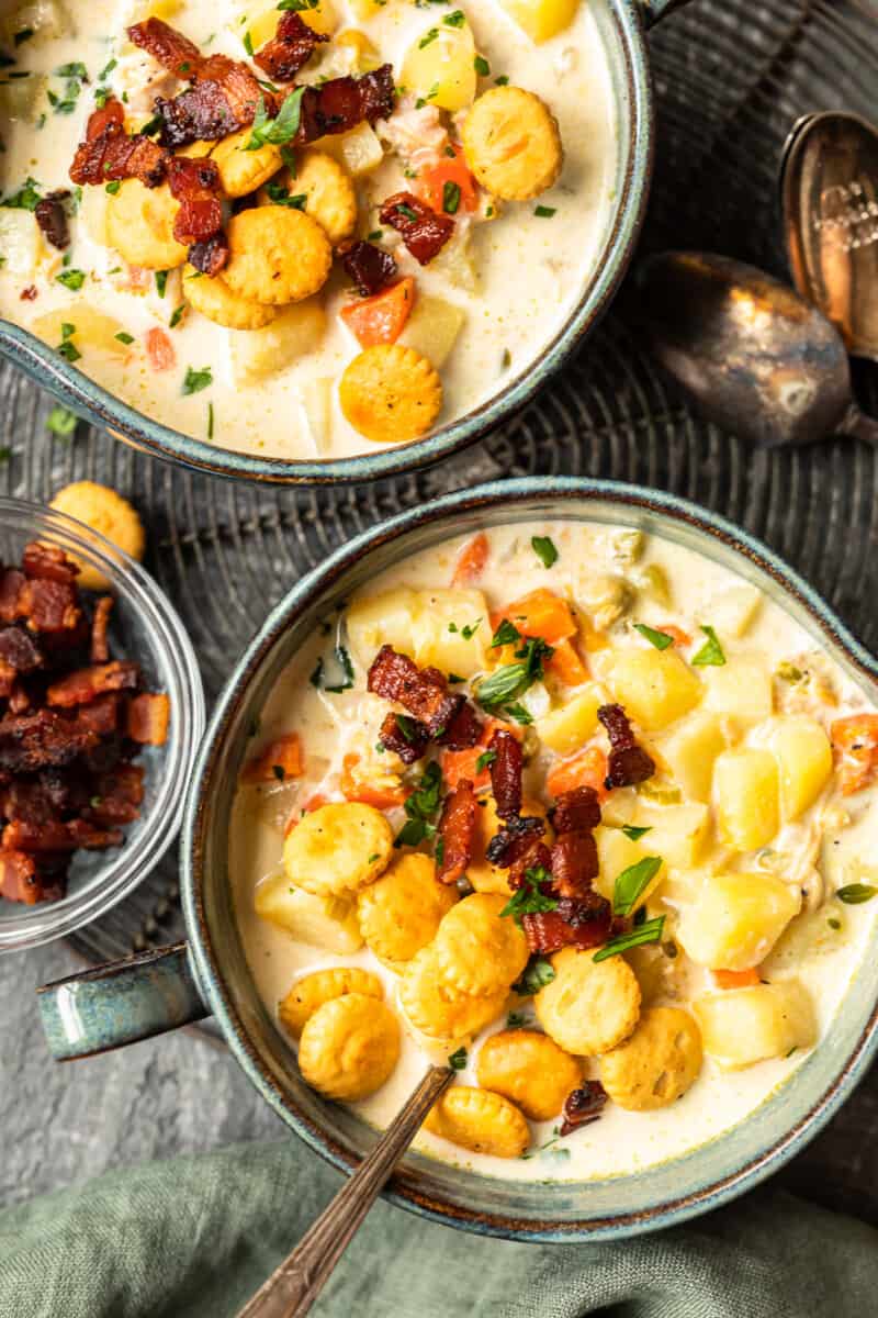 two bowls of chowder filled with veggies, clams, and potatoes