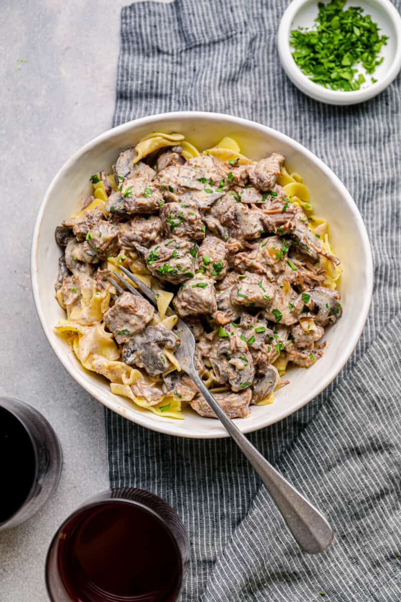 crockpot beef stroganoff in a white bowl with a fork.