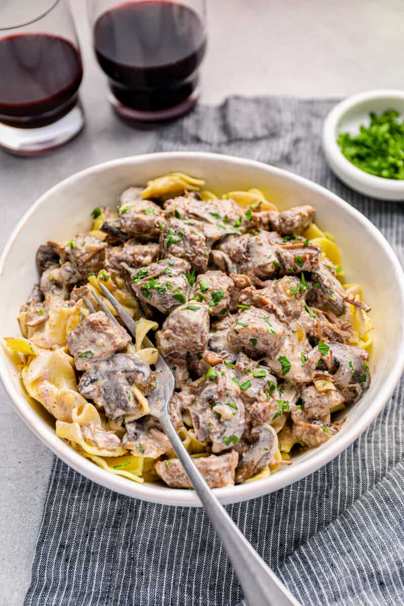 crockpot beef stroganoff in a white bowl with a fork.