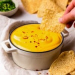 dipping a tortilla chip into a bowl of nacho cheese sauce