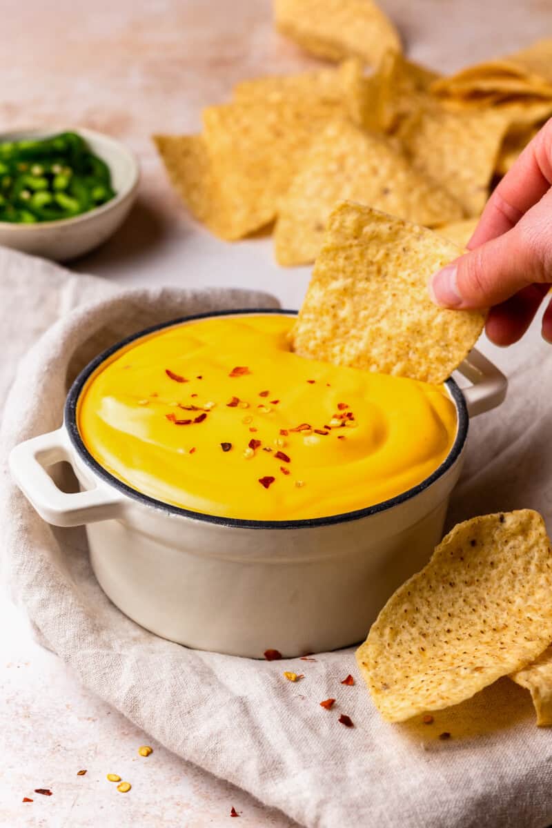 dipping a tortilla chip into a bowl of nacho cheese sauce