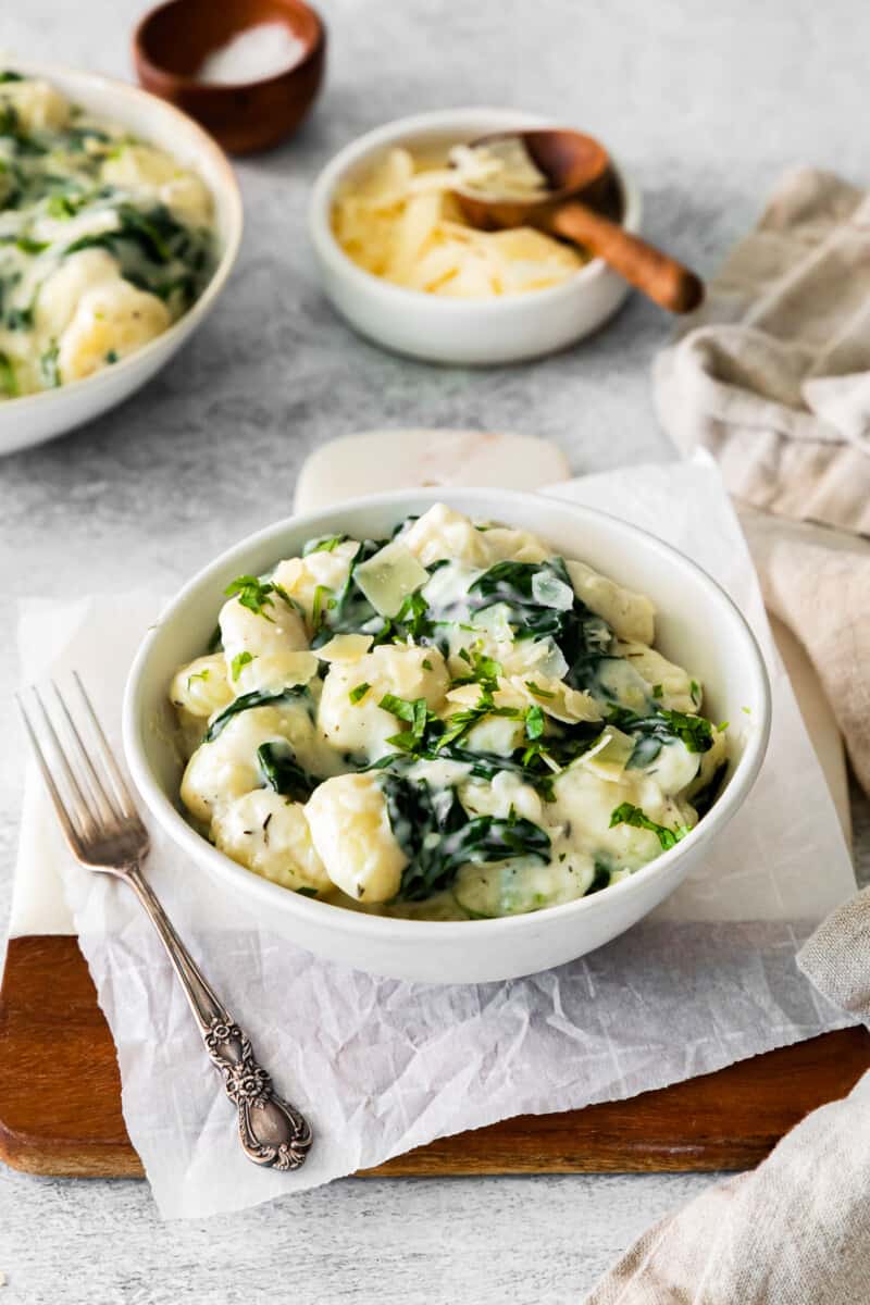 parmesan spinach gnocchi in a white bowl with a fork.