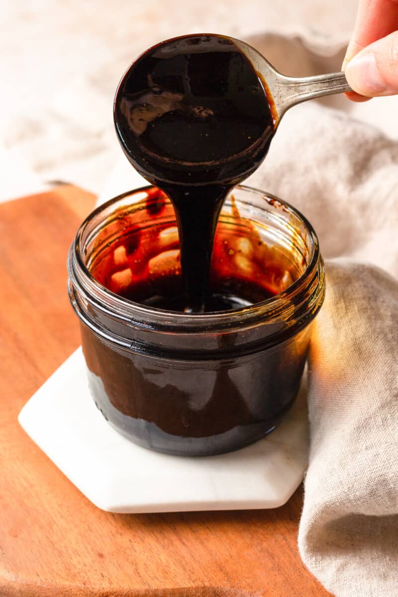 balsamic reduction dripping off a spoon into the jar of glaze