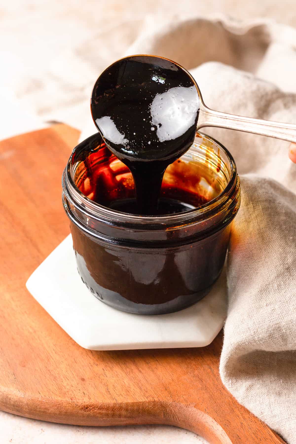 dipping a spoon into a jar of balsamic glaze