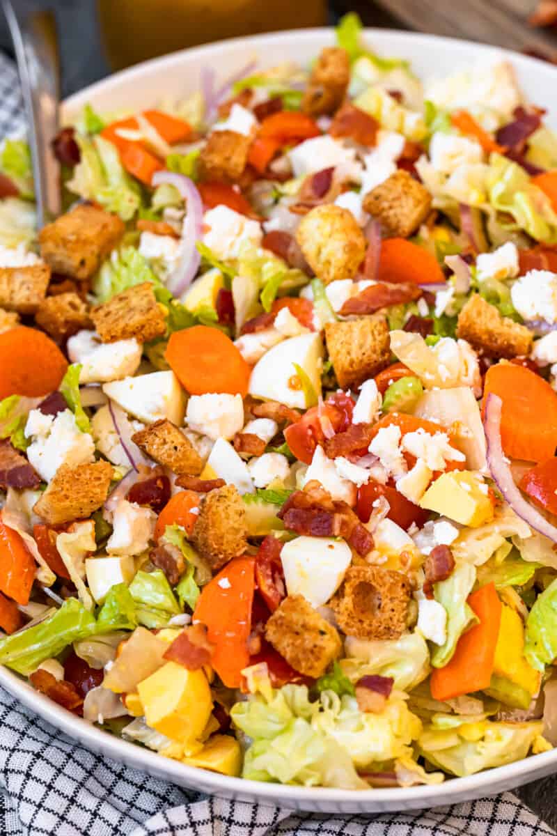 overhead view of chopped salad in a white serving bowl with a spoon.