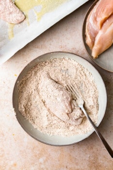 chicken breast in a bowl, being breaded for fried chicken