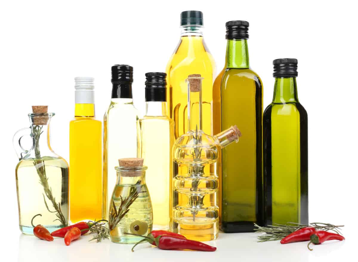 A group of bottles of olive oil and peppers.