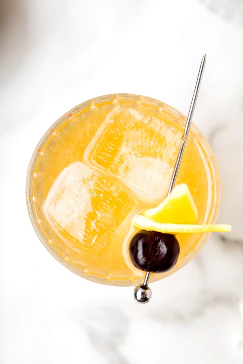 overhead view of whiskey sour with a cherry and lemon peel.