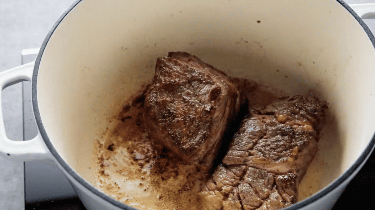 seared beef chuck roast pieces in a dutch oven.