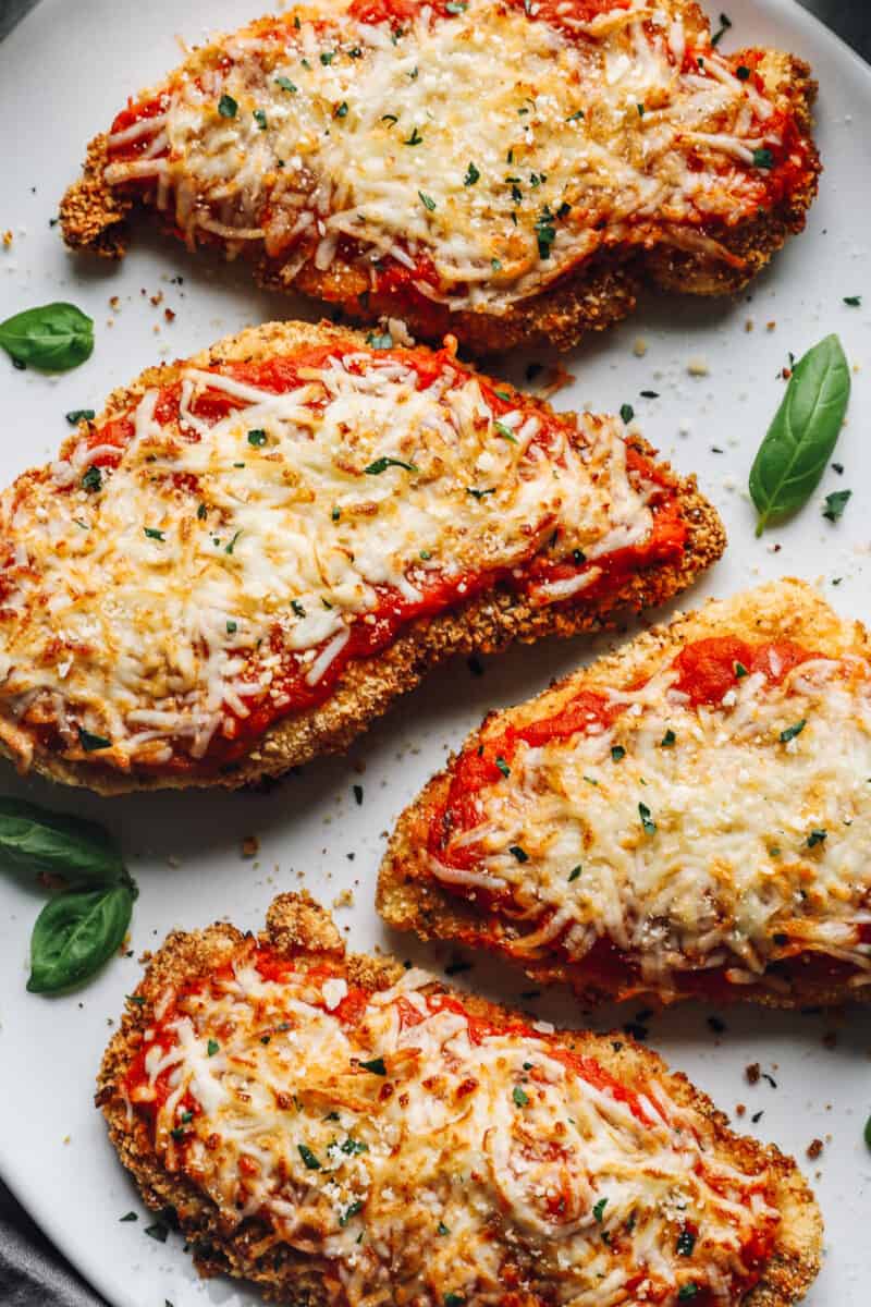 close up of 4 pieces of air fryer chicken parmesan on a white serving platter.