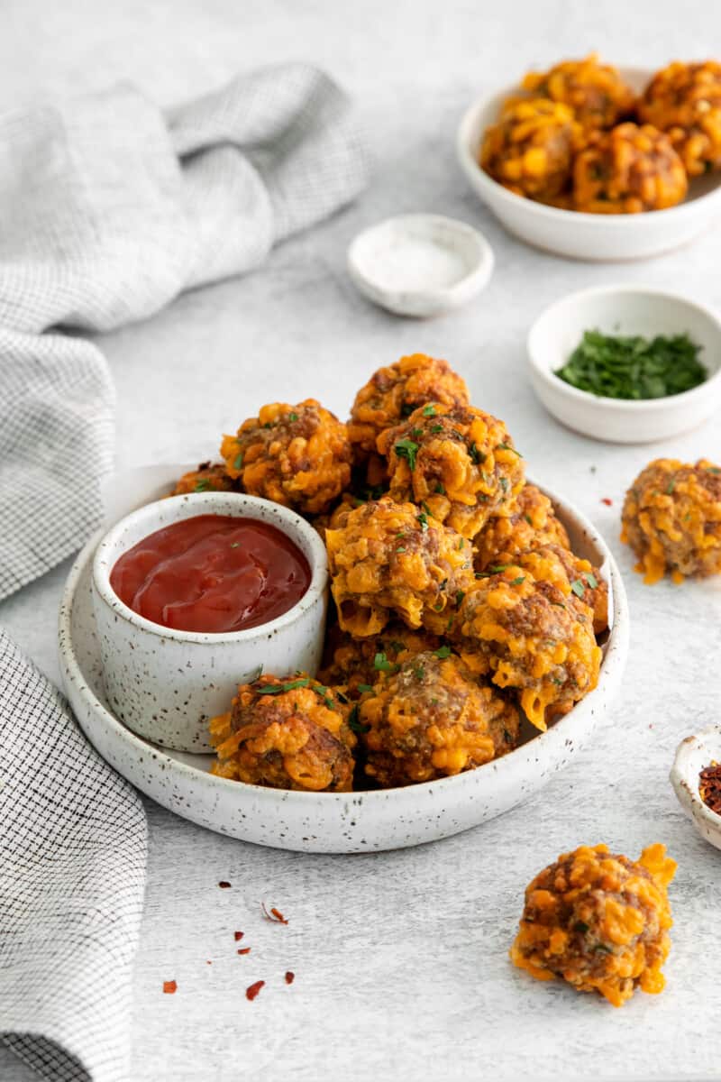 air fryer sausage balls on a white plate with sweet chili ketchup.