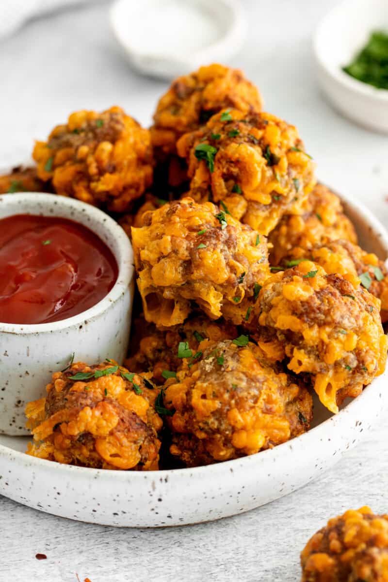 air fryer sausage balls on a white plate with sweet chili ketchup.