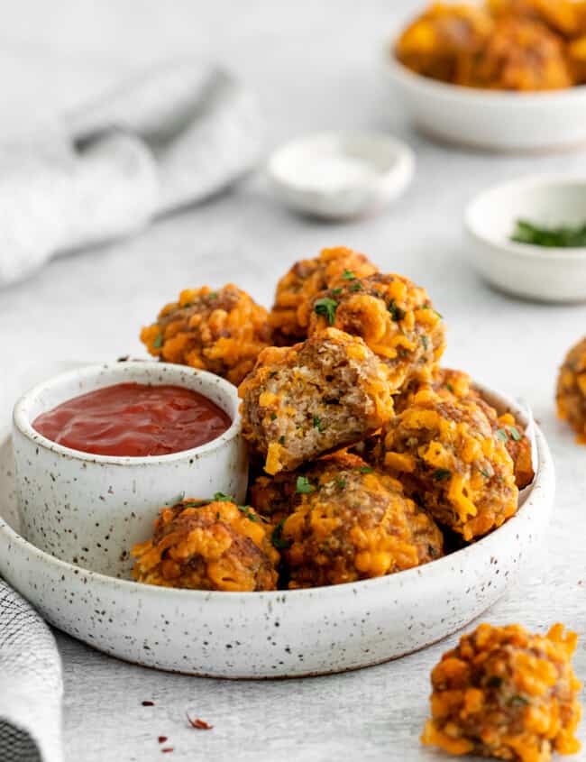 air fryer sausage balls on a white plate with sweet chili ketchup.