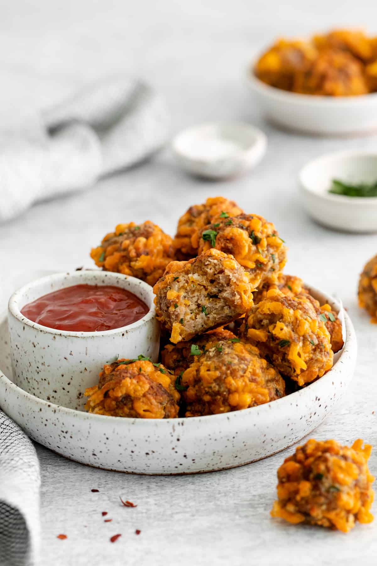 air fryer sausage balls on a white plate with sweet chili ketchup. 