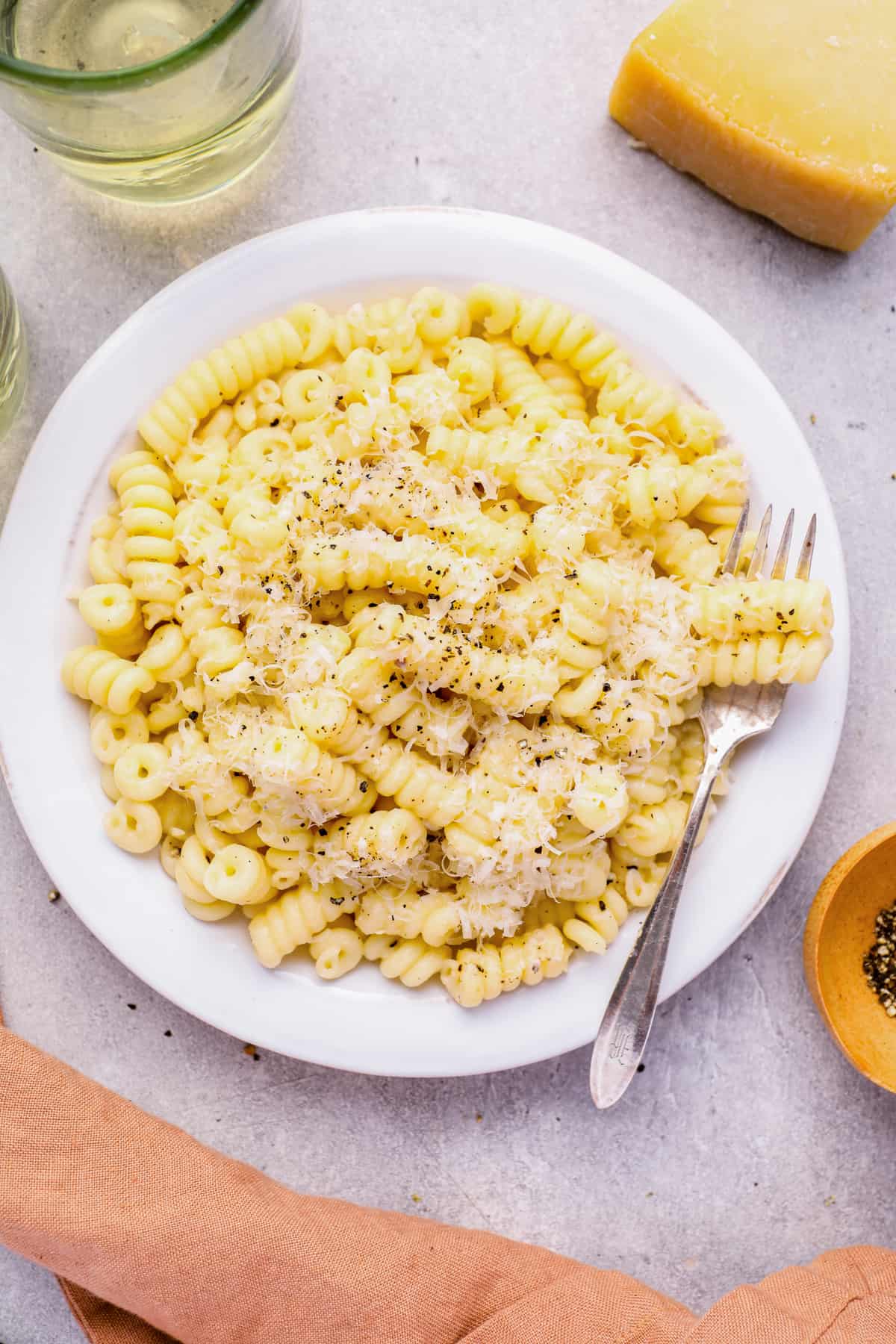 overhead view of cacio e pepe in a white bowl with a fork.