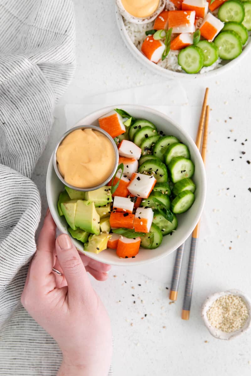 hand reaching towards a deconstructed sushi bowl