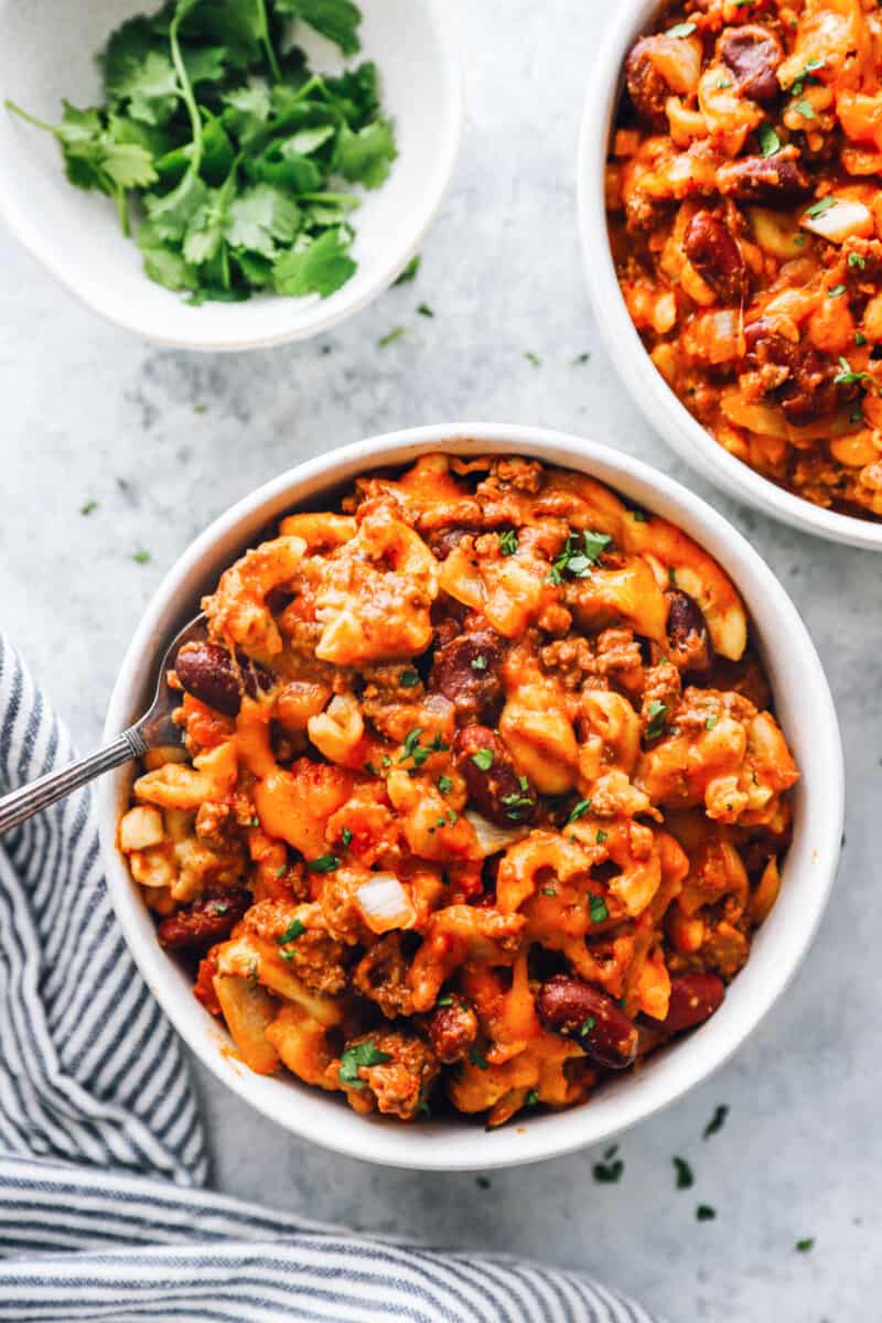 overhead view of crockpot chili mac in white bowls with a fork.