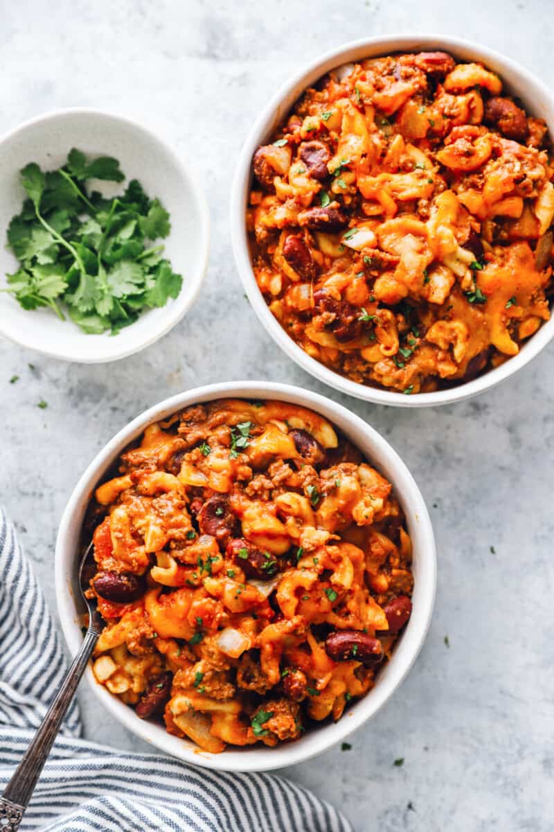 overhead view of crockpot chili mac in white bowls with a fork.