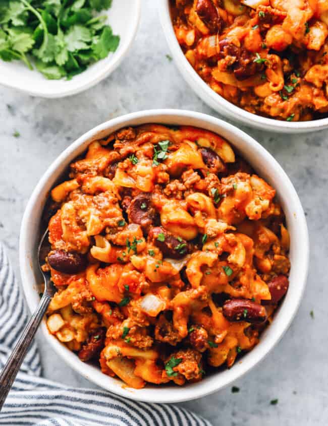 overhead view of crockpot chili mac in white bowls with a fork.