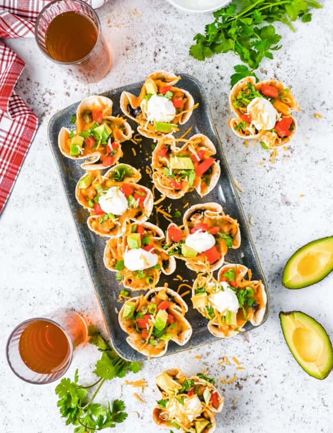 overhead view of 8 enchilada cups on a metal serving tray.