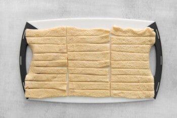 strips of dough lined up on a cutting board