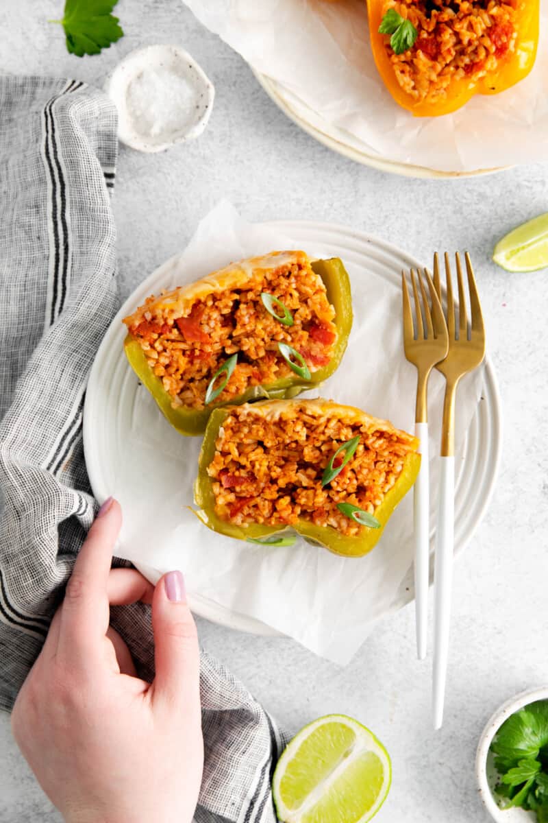 a hand holding a plate with a halved instant pot stuffed pepper on it.