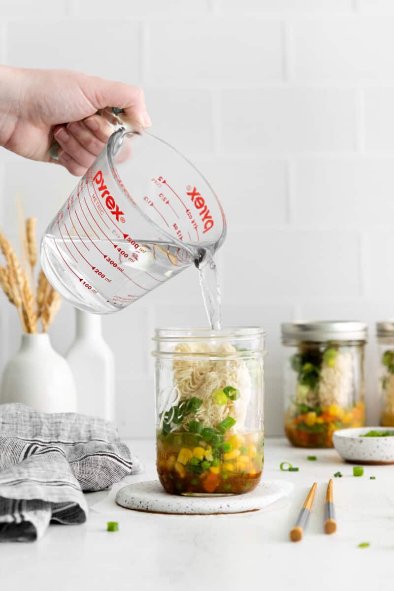 pouring water into a jar of instant ramen cups