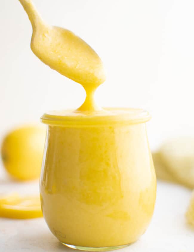 a spoon dipping into a jar of lemon curd