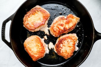 four pork chops sautéing in a skillet