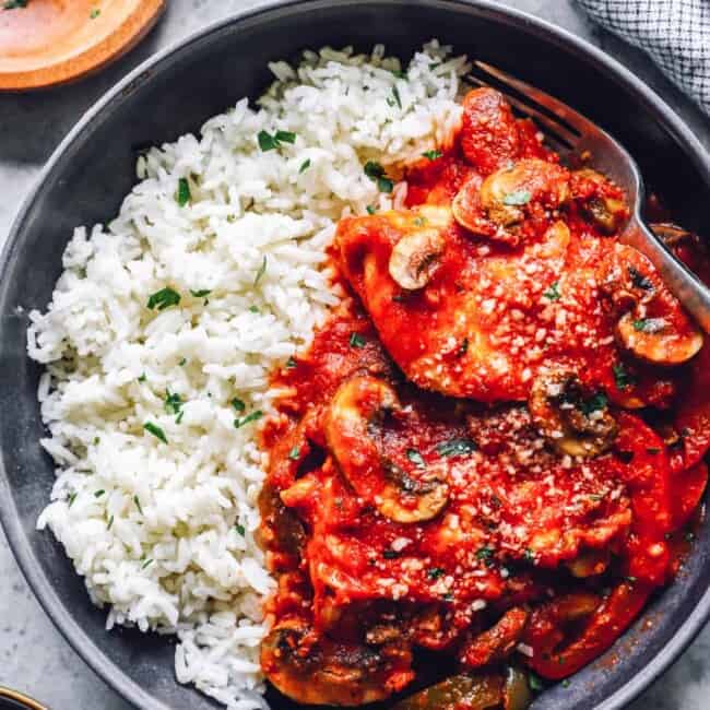 overhead view of crockpot chicken cacciatore with rice in a black bowl.