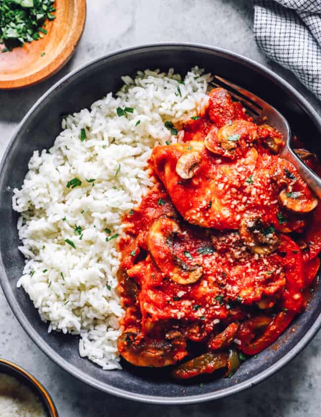 overhead view of crockpot chicken cacciatore with rice in a black bowl.