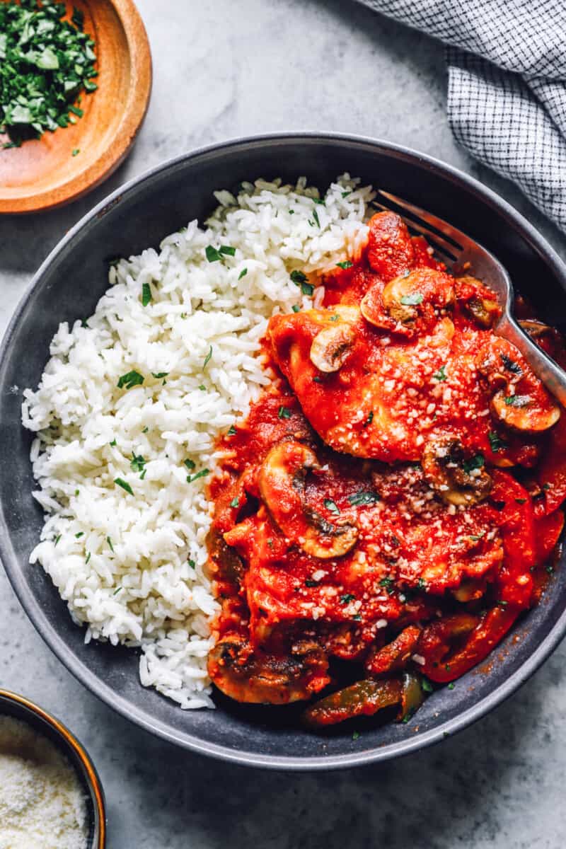 overhead view of crockpot chicken cacciatore with rice in a black bowl.