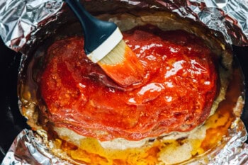 overhead view of glaze being brushed onto crockpot meatloaf in a crockpot.