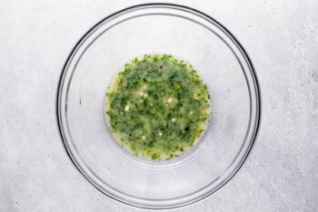 overhead view of melted butter and herbs in a glass bowl.