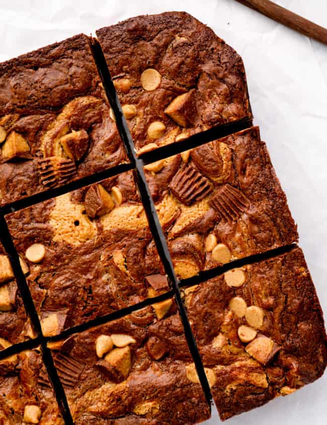 overhead view of cut peanut butter brownies on a white cutting board.