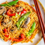 overhead view of vegetable lo mein on a white plate with chopsticks.