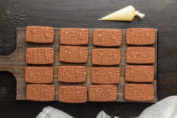 cookies lined up on a board with piping bag to frost